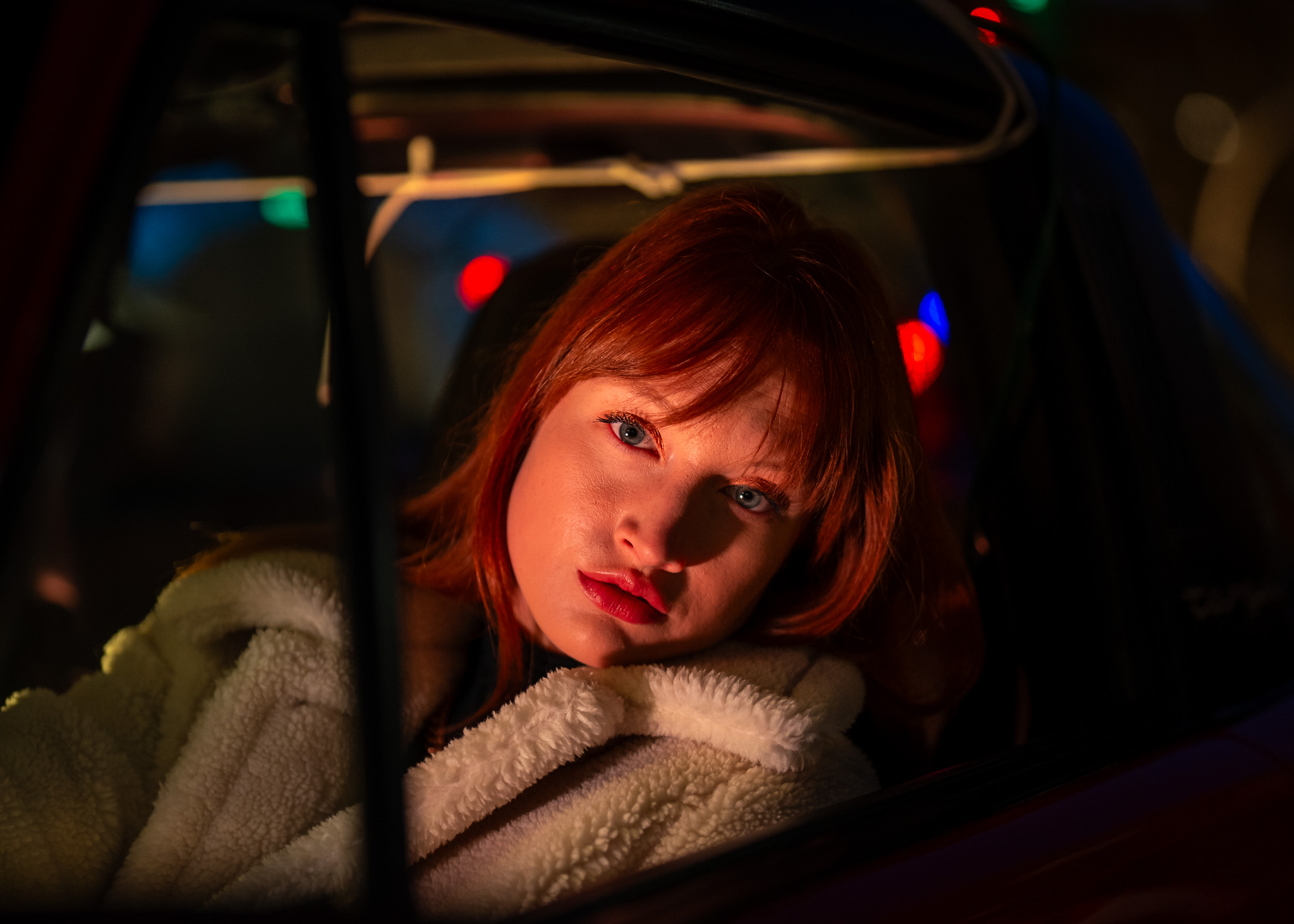 Red-haired woman photographed through a car window at night