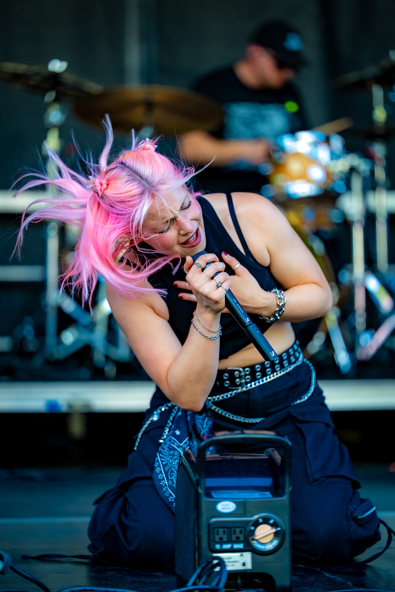 Pink-haired vocalist crouching at the front of the stage