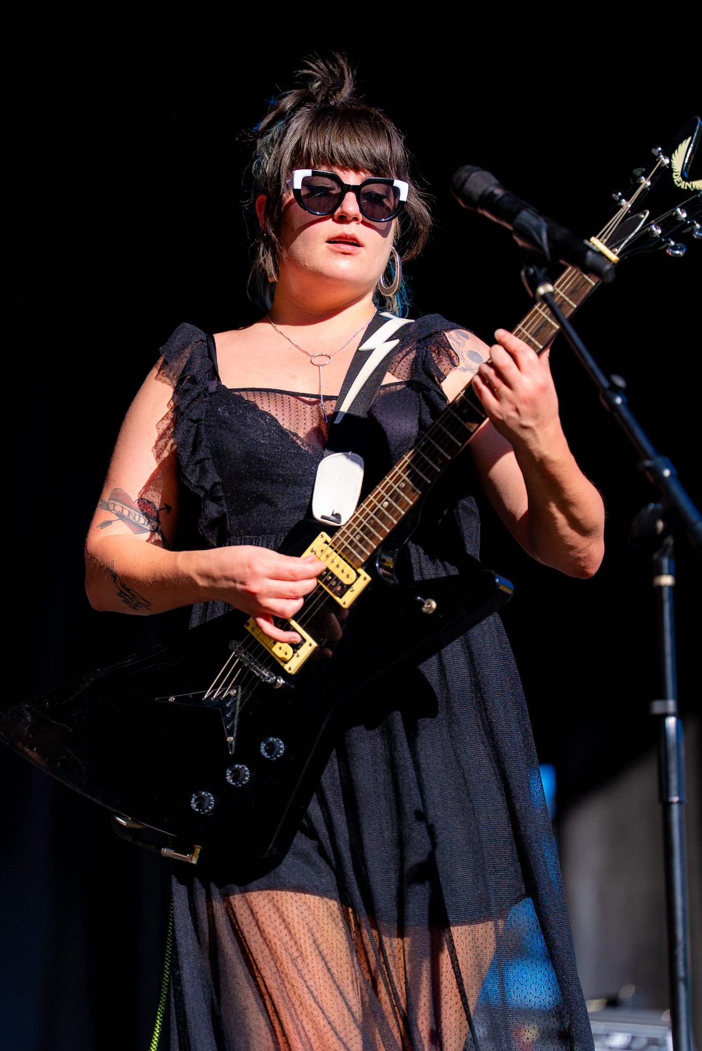 Guitarist performing in black on an outdoor stage