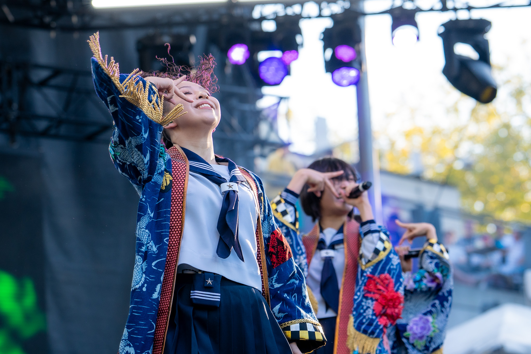ATARASHII GAKKO! performing beneath blue stage light