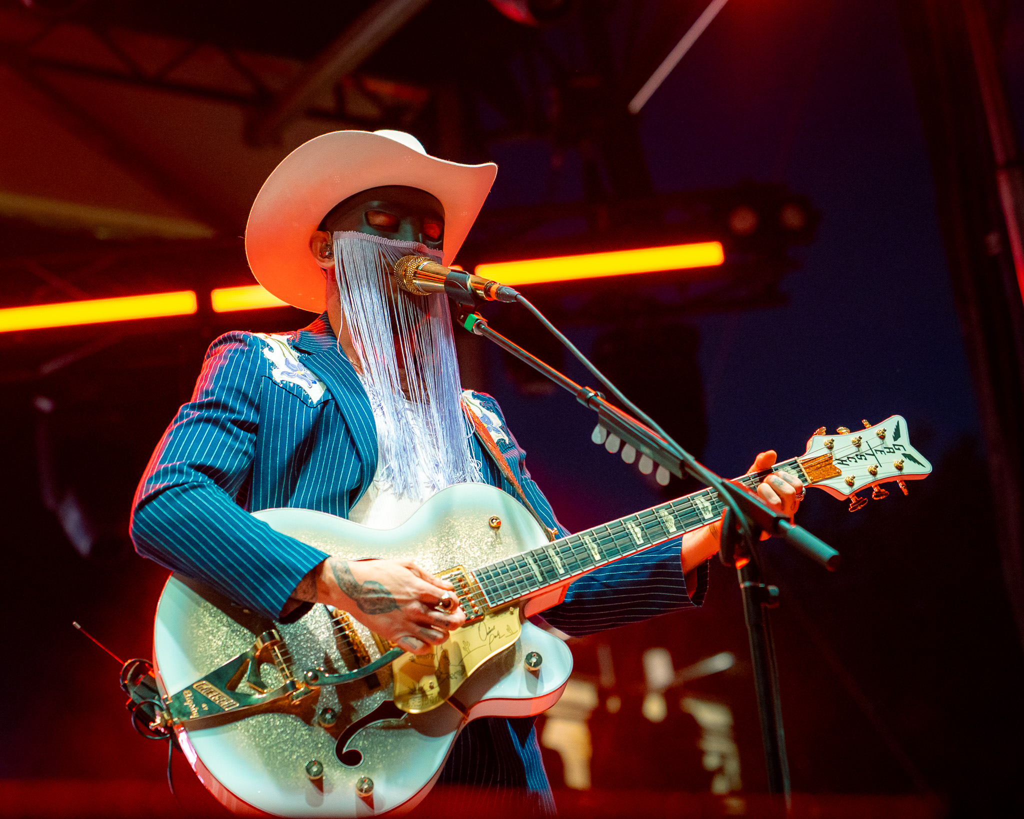 Orville Peck performing in a blue western suit and mask