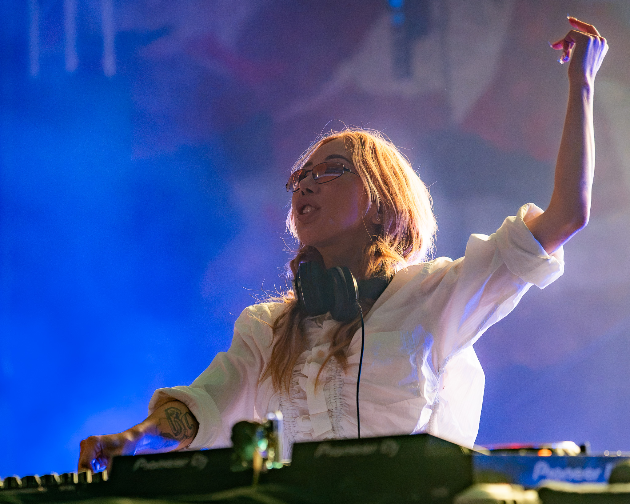 TOKiMONSTA raising an arm through blue stage haze