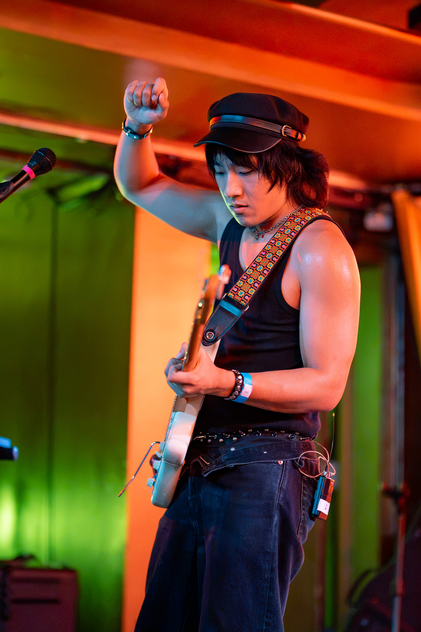 A CHANPAN guitarist raises a hand while playing beneath orange and green light
