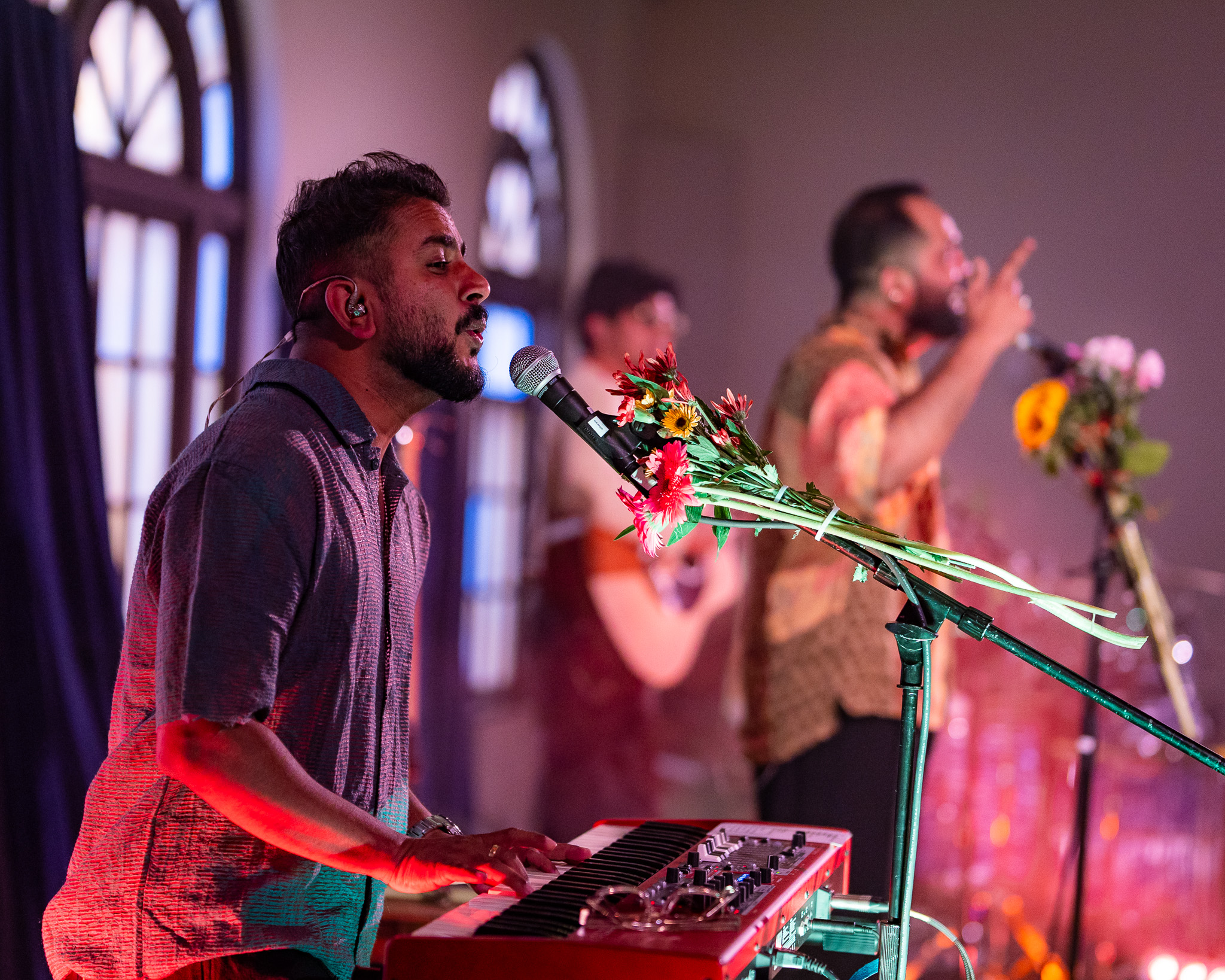 The keyboardist sings into a flower-wrapped microphone