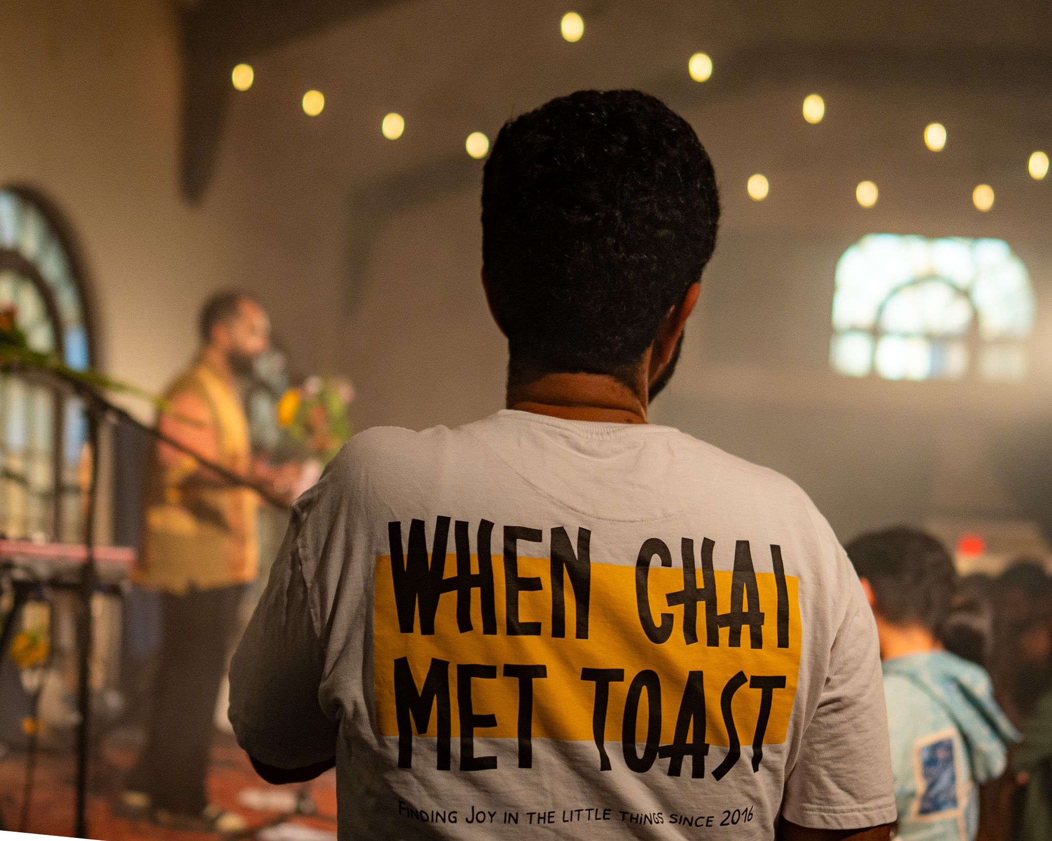 A fan wearing a When Chai Met Toast tour shirt watches the band