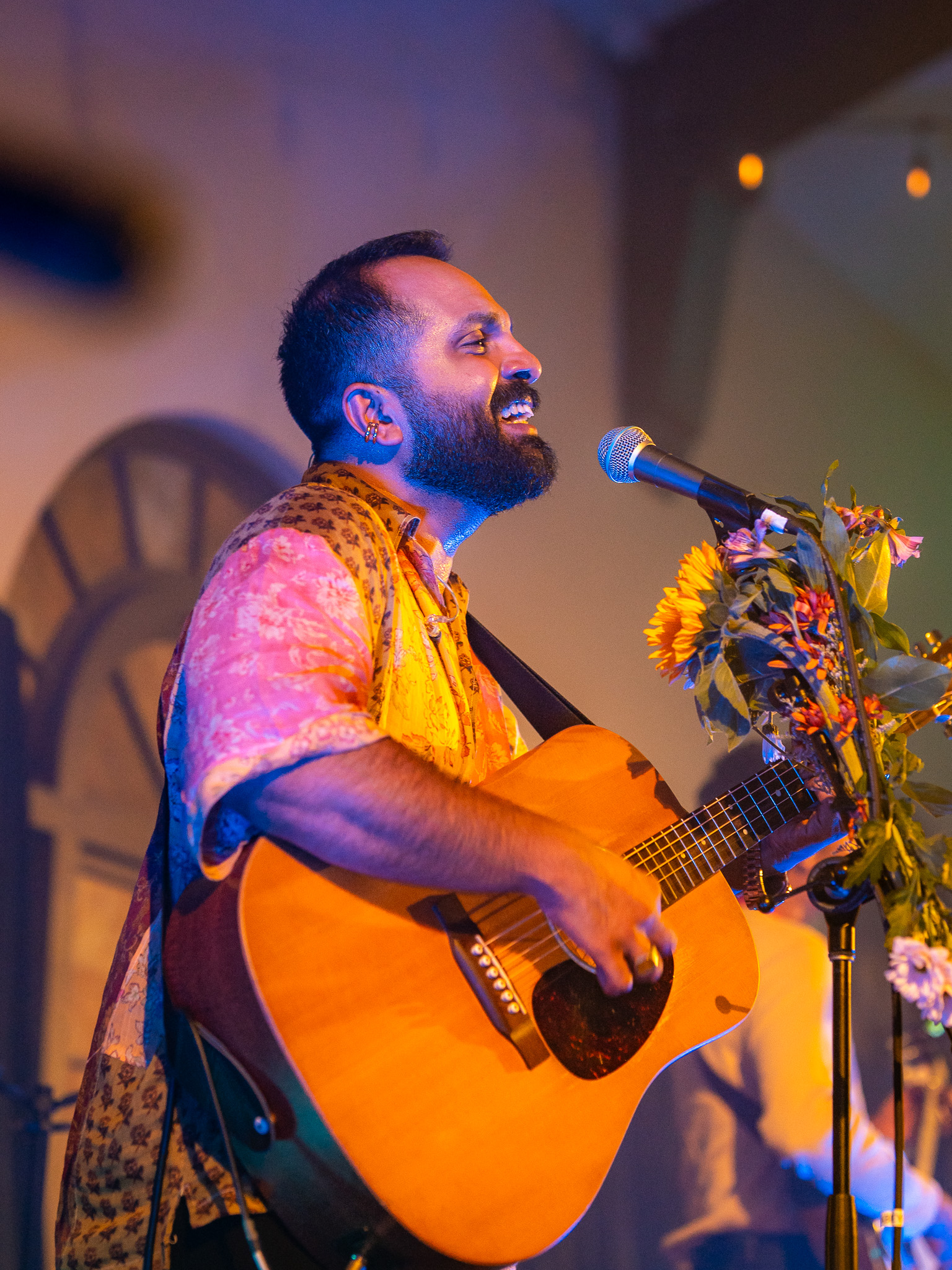 The lead singer of When Chai Met Toast smiles at a flower-wrapped microphone